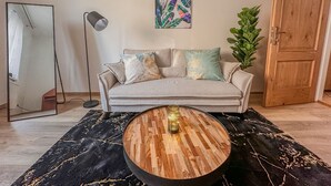 A living room with a sofa, a round coffee table, a floor lamp, a mirror, a door, and a plant. - Central Cozy & Charming Residence 3min from Riverside Prague (Hlavní mesto Praha)