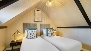 A bedroom with two beds, a ceiling fan, and a framed picture on the wall.