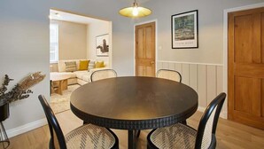 A dining area with a round table, four chairs, and a hanging light fixture.