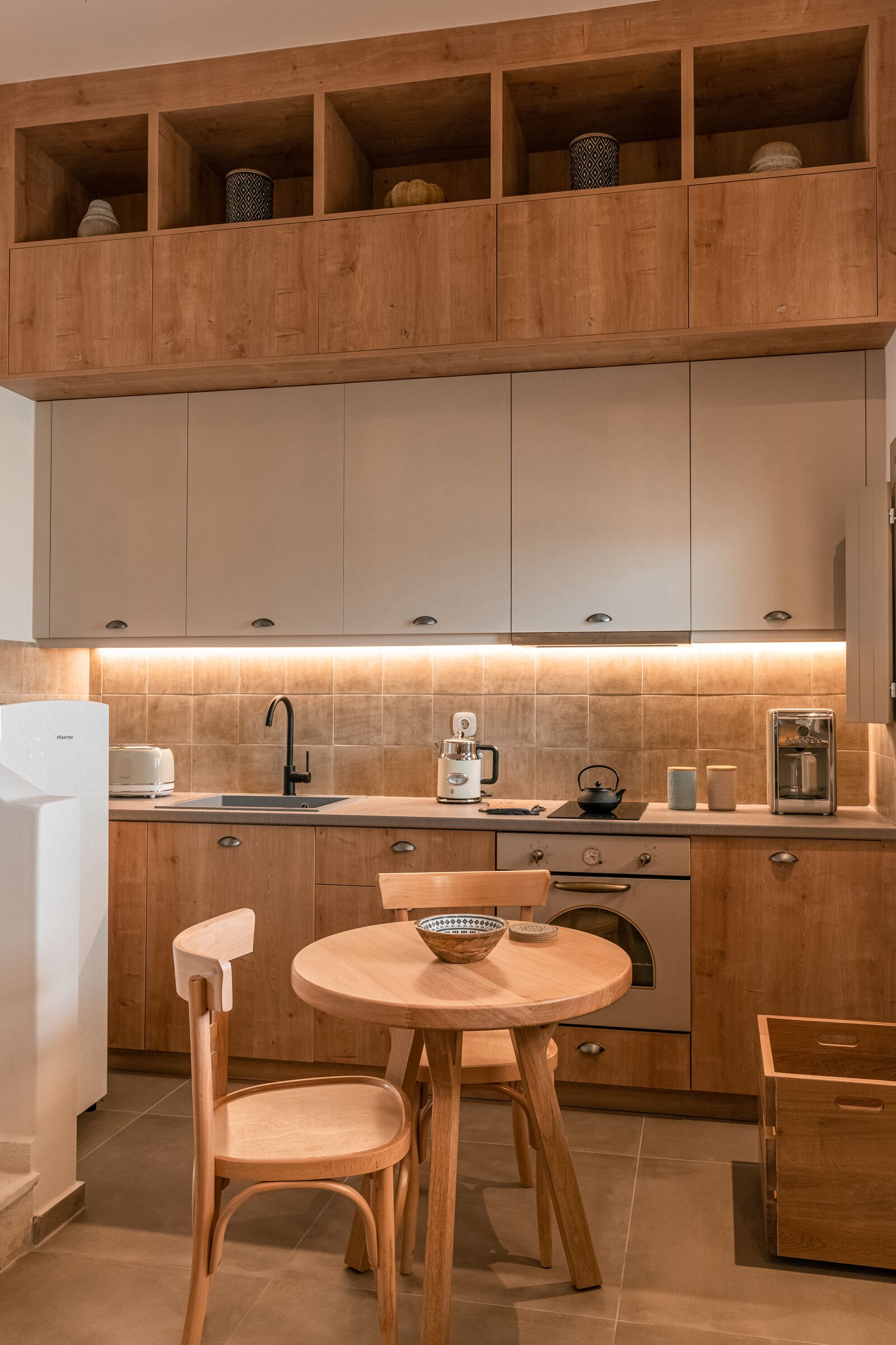A modern kitchen with wooden cabinets, a round dining table, and a built-in oven.