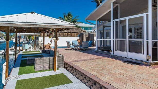 A covered outdoor area with a pool, seating, and a building with large windows.