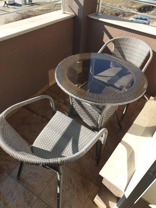 A balcony with wicker furniture, including a round table and two chairs. - 2-bed - Sleeps 4 - w Parking (Blagoevgrad)
