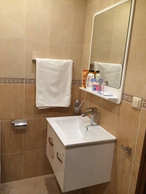 A bathroom with a white sink, a mirror, and a towel hanging on the wall. - 2-bed - Sleeps 4 - w Parking (Blagoevgrad)
