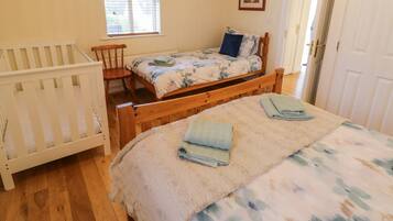 A bedroom with a wooden bed, a crib, a window, and a door.