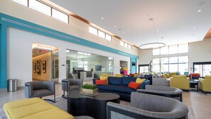 A spacious lobby with modern furniture, a central seating area, and large windows providing natural light.
