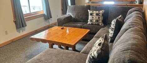 A living room with a sectional sofa, a wooden coffee table, and a ceiling fan.
