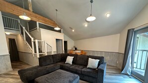A spacious living area with a large sectional sofa and ottoman, a staircase, and a dining area. - Manhattan Beach Lodge (Crosslake)