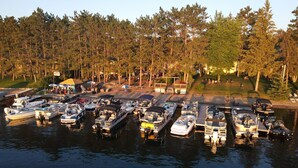 A marina with multiple boats docked, surrounded by a forested area. - Manhattan Beach Lodge (Crosslake)