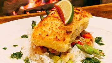 A plate of food with rice, broccoli, and a piece of breaded fish, garnished with a slice of lime.