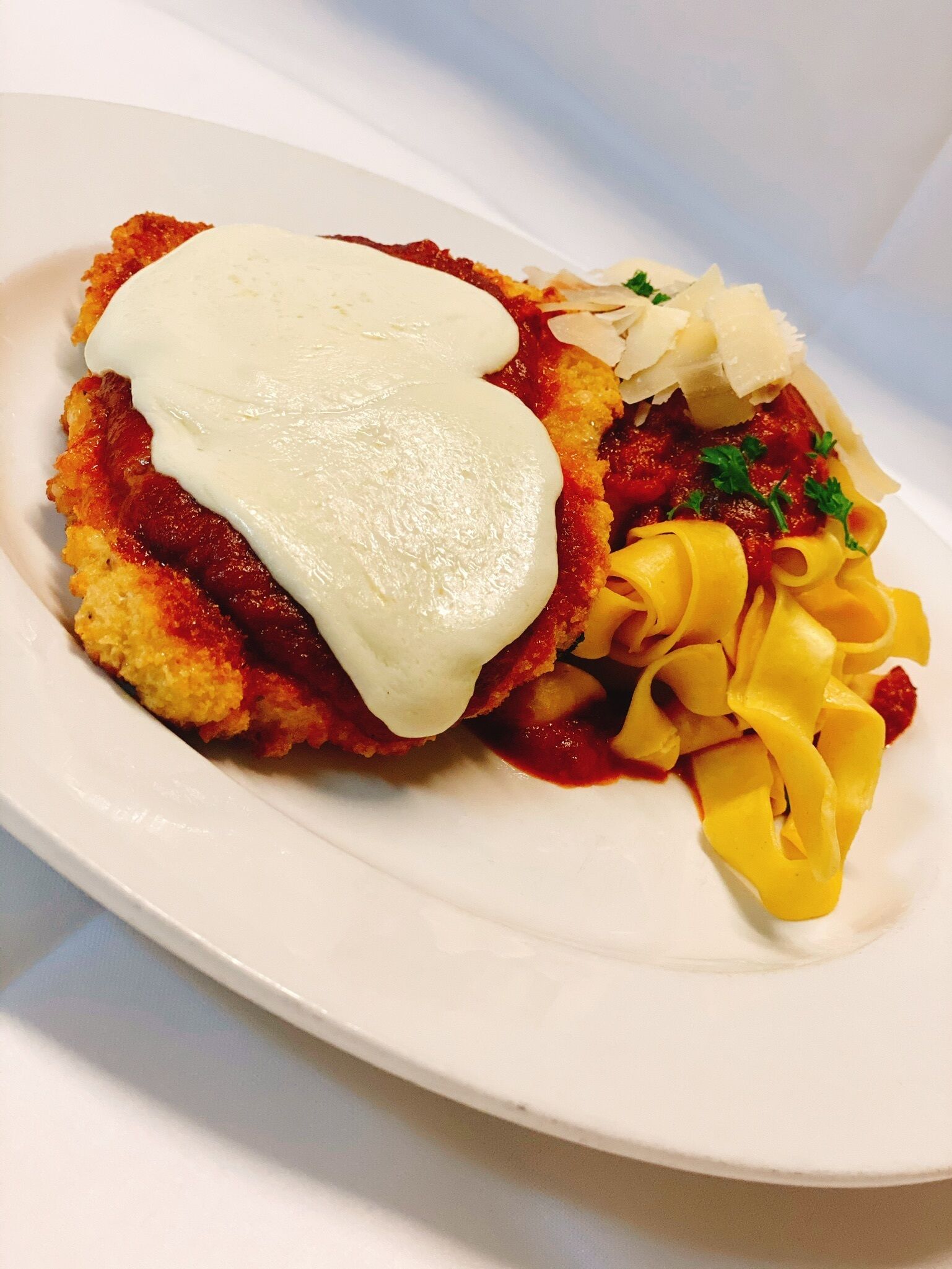 A plate of food with breaded cutlet, sauce, and pasta.