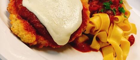 A plate of food with breaded cutlet, sauce, and pasta.