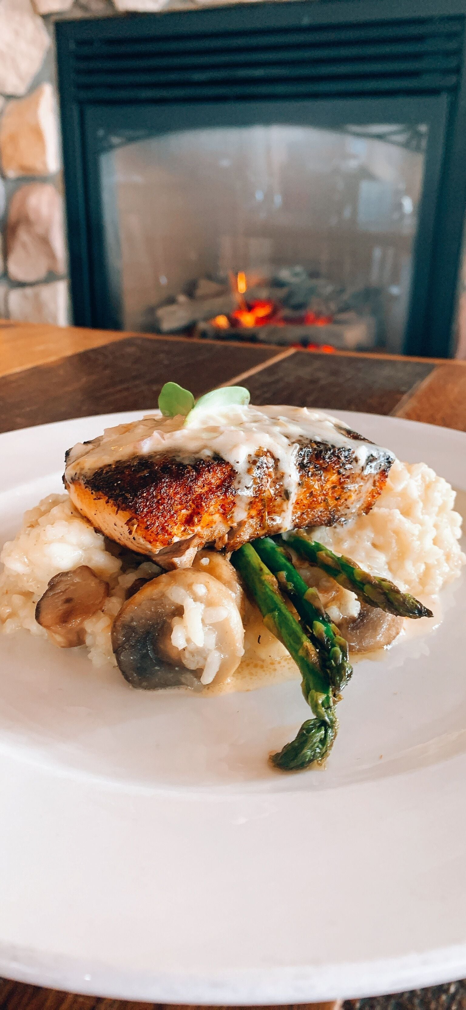 A plate of food with grilled fish, mushrooms, and asparagus on a white plate.