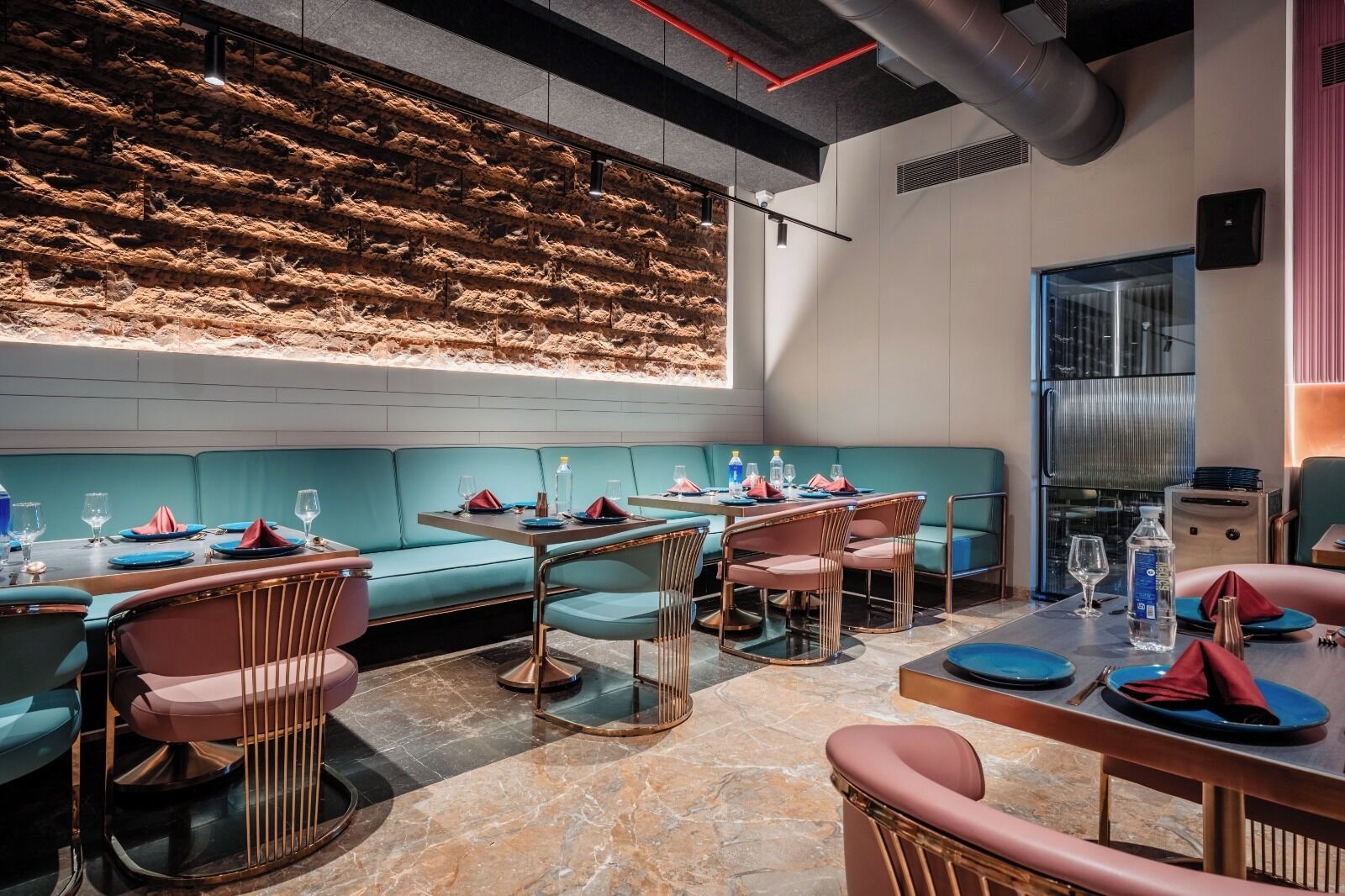 A restaurant with teal seating, marble flooring, and a wall with a textured pattern.