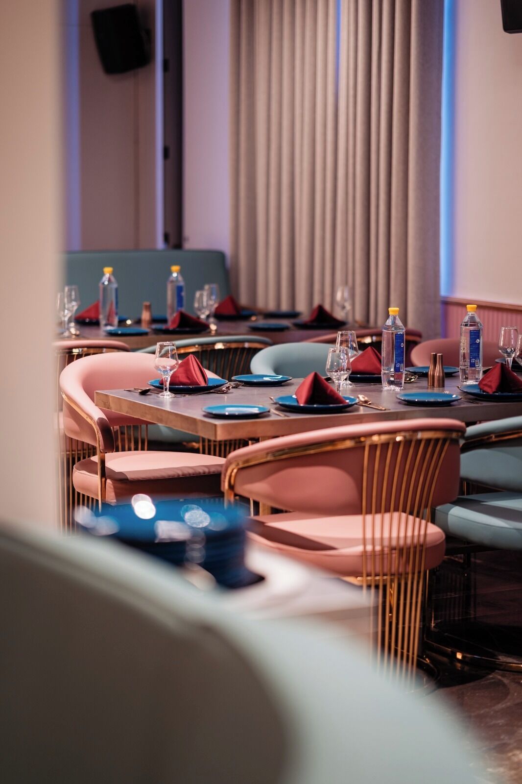A dining area with round tables, chairs, and neatly set tables with plates, glasses, and water bottles.