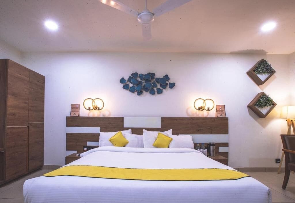 Habitación de hotel con cama, armario de madera, luces fijadas en la pared y decoración mural.