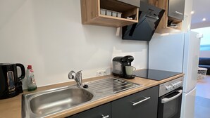 Eine moderne Küche mit Spüle aus Edelstahl, einer Kaffeemaschine und einem eingebauten Backofen.