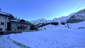 A snow-covered landscape with a building featuring a stone facade and wooden balconies. - San Simone rentals - VALS30 (Valleve)
