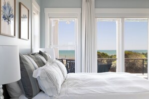 A bedroom with a large bed, a view of the ocean, and a balcony with a railing. - Salt & Light, Oceanfront House in Indian Beach, NC! (Indian Beach)