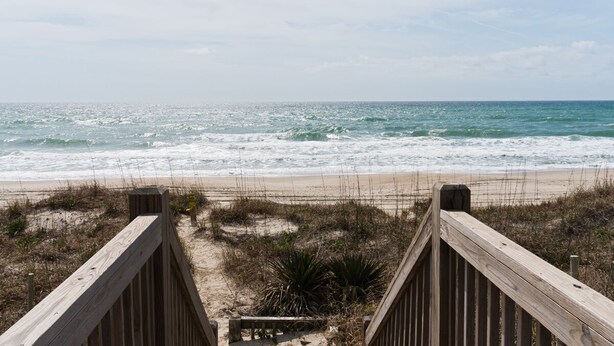 A wooden boardwalk leading to a beach with waves crashing onto the shore. - Sea Castle East, Oceanfront Duplex in Emerald Isle, NC! (Emerald Isle)