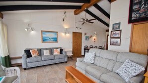 A living room with two grey sofas, a wooden coffee table, and a white wicker chair. - Sea Castle East, Oceanfront Duplex in Emerald Isle, NC! (Emerald Isle)