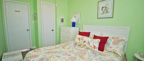 A bedroom with a bed, a ceiling fan, a dresser, and a framed picture on the wall.