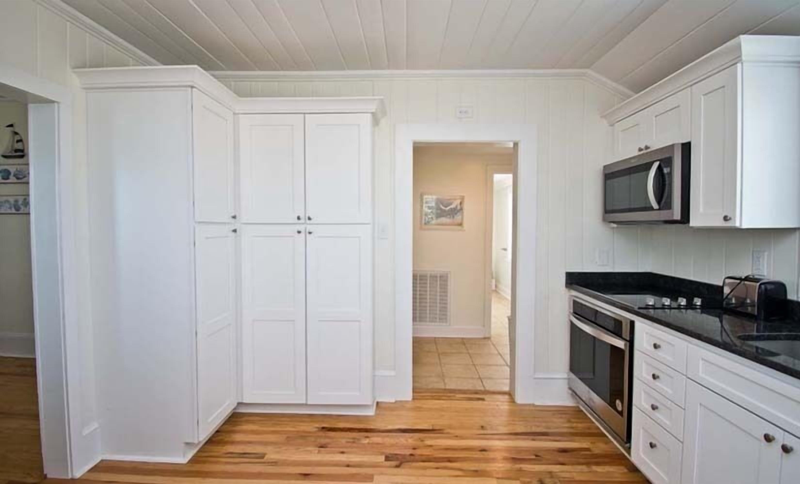 A kitchen with white cabinets, a microwave, and a stove.