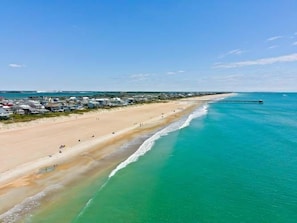 Une zone côtière comprenant une plage, une jetée et une rangée de bâtiments le long du rivage.
