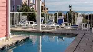 Un espace piscine avec des chaises longues et vue sur l’océan.