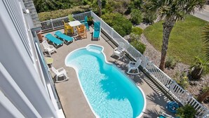 A swimming pool with lounge chairs and a deck area, surrounded by a white fence and palm trees. - Sea Notes, Almost Oceanfront House in Emerald Isle, NC! (Emerald Isle)