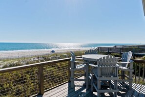 A deck with a table and chairs overlooking a beach. - Sea Watcher, Oceanfront House in Emerald Isle, NC! (Emerald Isle)