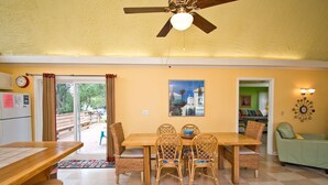 A dining area with a wooden table and chairs, a ceiling fan, and a view of the outdoors. - Sunbeam, Oceanside House in Emerald Isle, NC! (Emerald Isle)