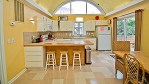A kitchen with a large island, white cabinets, and a view through the window. - Sunbeam, Oceanside House in Emerald Isle, NC! (Emerald Isle)