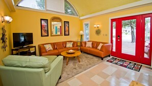 A living room with a sectional sofa, a television, and a red door. - Sunbeam, Oceanside House in Emerald Isle, NC! (Emerald Isle)