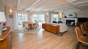 Un salon spacieux doté d’un plancher en bois, un coin repas avec une table et des chaises, un canapé et une cheminée.