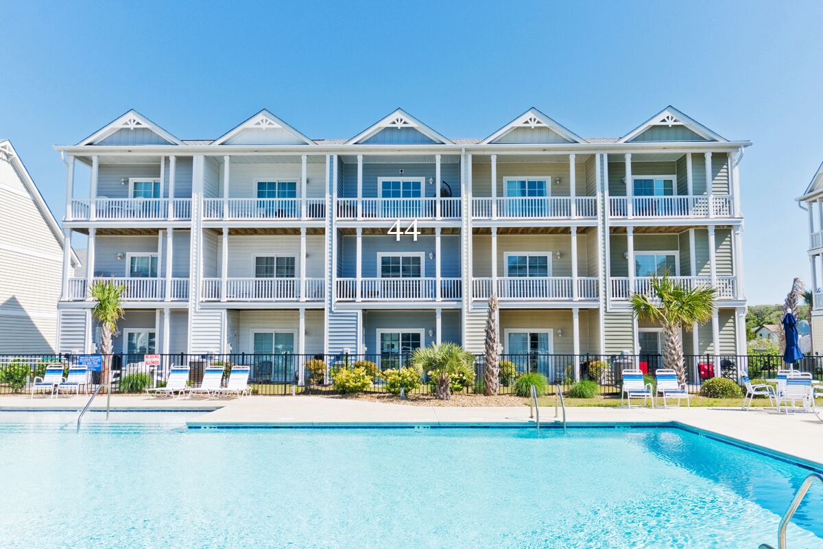 A multi-story hotel with a pool in front.