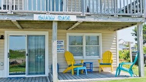 A beach house named Sunny Daze with a covered porch, two Adirondack chairs, and a sign for a water treatment company. - Sunny Daze, Almost Oceanfront Duplex in Atlantic Beach, NC! (Atlantic Beach)