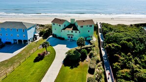 Un grand bâtiment à deux étages doté d’une cour intérieure, entouré d’une végétation luxuriante et offrant une vue sur la plage.