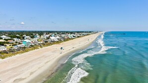 Une ville côtière avec une plage, des maisons et une jetée qui s’avance dans l’océan.