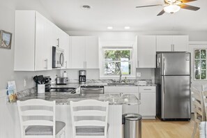 Una cocina moderna con armarios blancos, un refrigerador de acero inoxidable y una encimera de mármol.
