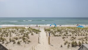 Una playa con un camino de arena que lleva al agua, un puesto de salvavidas y un arco azul.