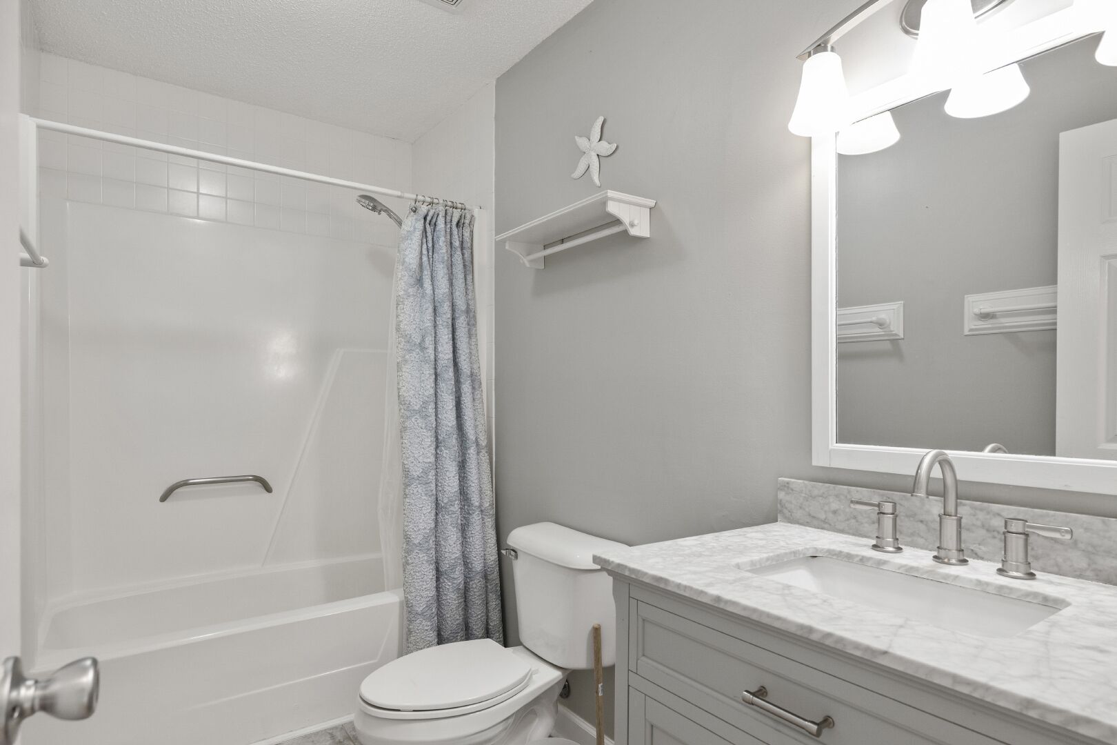 A bathroom with a shower, toilet, sink, and vanity.