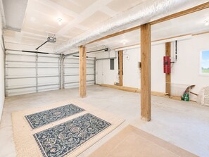 Un garage spacieux doté d’un sol en béton, de poutres en bois et d’un extincteur rouge.