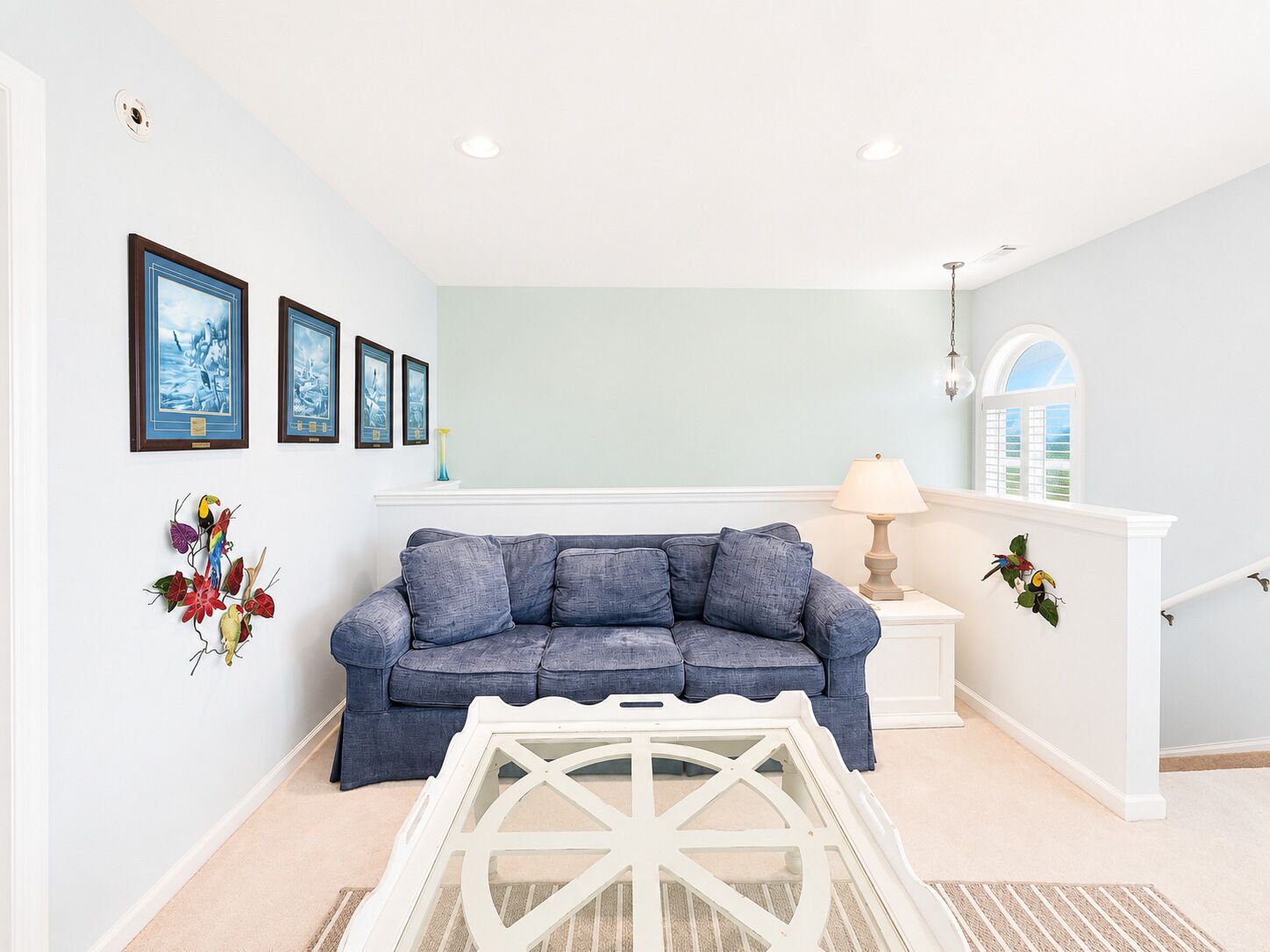 A living room with a blue sofa, a white coffee table, and wall art.