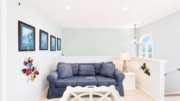 Un salon avec un canapé bleu, une table basse blanche et des œuvres d’art murales.