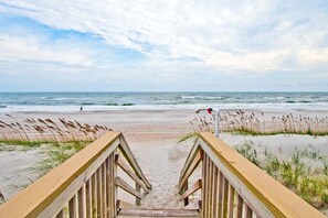 A wooden boardwalk leading to a beach with waves in the background. - Sweetwater, Oceanfront House in Emerald Isle, NC! (Emerald Isle)