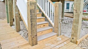 A wooden deck with a staircase leading to a covered area. - Swiss House, Oceanfront Home in Atlantic Beach, NC! (Atlantic Beach)