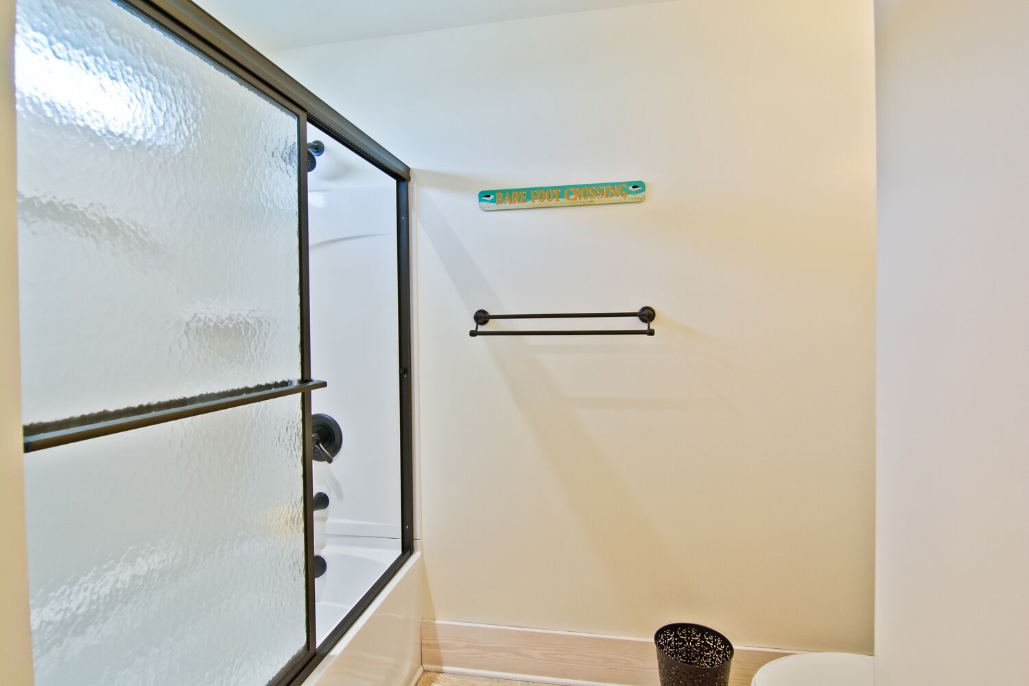 A bathroom with frosted glass doors, a towel rack, and a sign indicating a baby changing area.