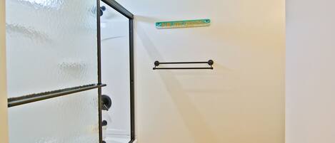 A bathroom with frosted glass doors, a towel rack, and a sign indicating a baby changing area.