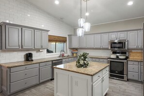 Una cocina moderna con armarios grises, encimera de granito, horno empotrado y microondas.