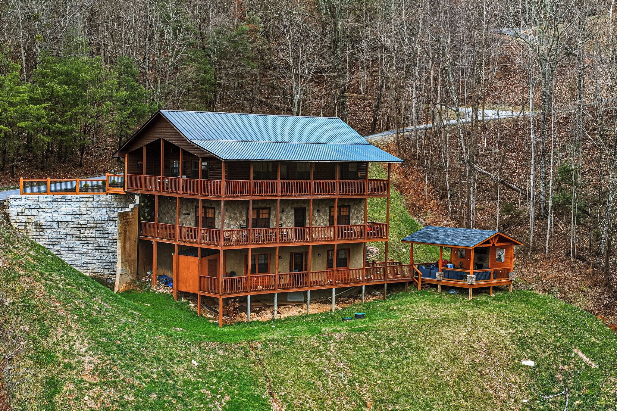 Une cabane en rondins à deux étages, dotée d’un balcon et entourée d’un paysage boisé.